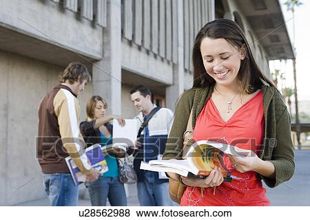 Female university student holding book, outdoors View Large Photo Image Stock Photo - Female university student holding book, outdoors. Fotosearch