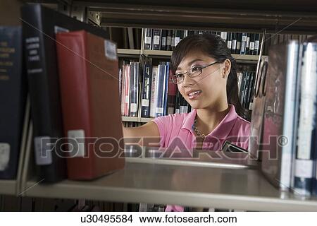 Picture - Female University student in library. Fotosearch