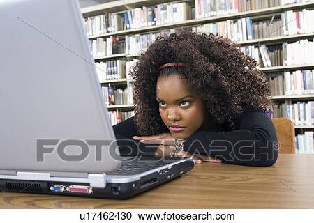 Stock Image - Female university student learning in library. Fotosearch