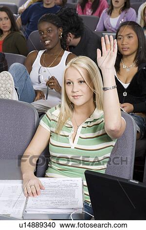 Stock Image - Female University student raising hand in class. Fotosearch