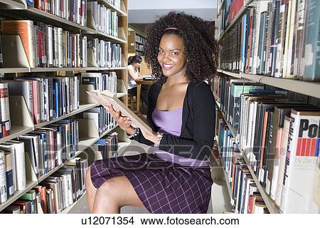 Picture - Female university student studying in library, portrait. Fotosearch