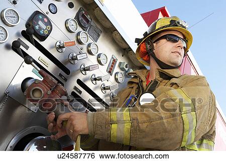 Stock Photograph - Fire fighter connecting hose to fire truck instrument panel. Fotosearch
