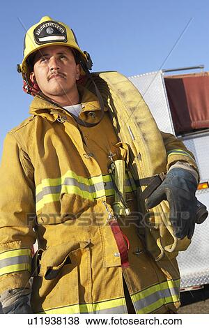 Stock Photo - Fire fighter standing with hose on shoulder. Fotosearch