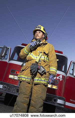Fire fighter using two way radio in front of fire engine, low angle view View Large Photo Image Stock Photo - Fire fighter using two way radio in front of fire engine, low angle view. Fotosearch