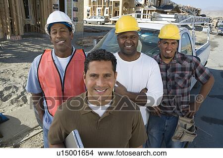 Picture - Four construction workers standing in front of car on construction site. Fotosearch