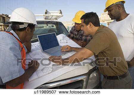 Stock Photo - Four construction workers standing in front of car on construction site. Fotosearch