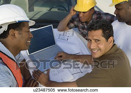 Four construction workers standing in front of car on construction site View Large Photo Image Stock Photography - Four construction workers standing in front of car on construction site. Fotosearch
