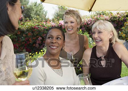 Four mature elegant women chatting at garden party View Large Photo Image Stock Photography - Four mature elegant women chatting at garden party. Fotosearch