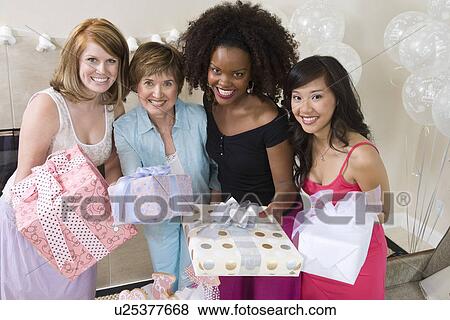 Friends standing Together holding gifts at party View Large Photo Image Stock Photo - Friends standing Together holding gifts at party. Fotosearch