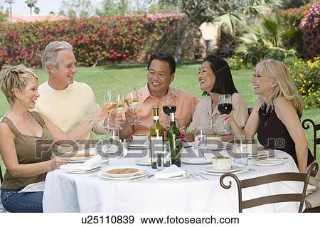 Stock Photo - Friends toasting at outdoor table. Fotosearch