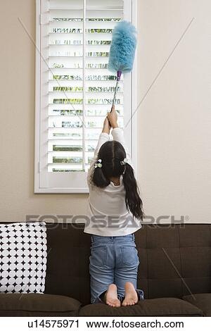 Stock Image - Girl (10-12) dusting window. Fotosearch