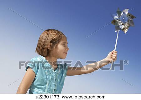 Stock Image - Girl (5-9) with pinwheel, side view, portrait. Fotosearch