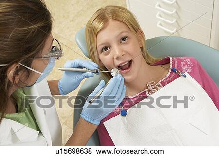 Stock Photo - Girl (7-10) having teeth examined at dentists. Fotosearch
