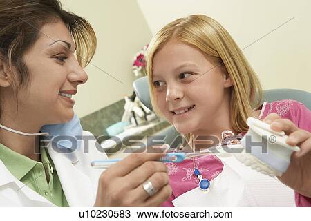 Stock Image - Girl (7-10) with dentist in surgery. Fotosearch