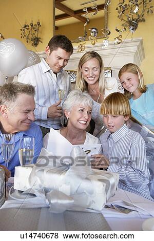 Stock Photo - Grandmother smiling at party with whole family. Fotosearch