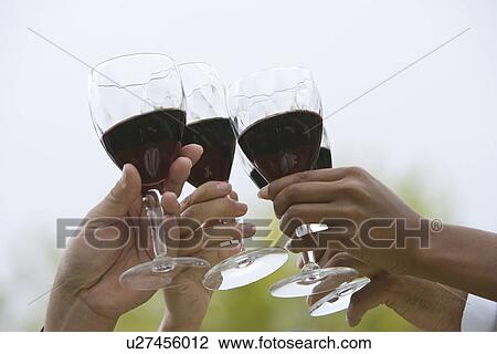Stock Image - Group of friends toasting outdoors, close-up. Fotosearch