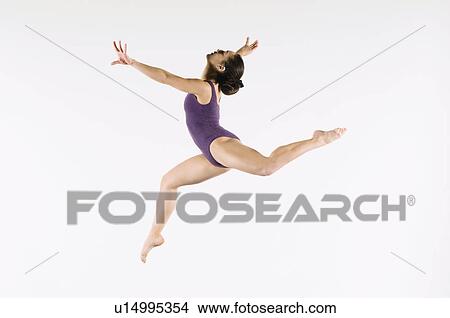 Picture - Gymnast (13-15) leaping in air, side view. Fotosearch