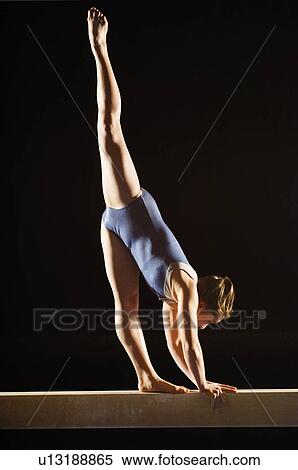 Stock Photography - Gymnast (13-15) striking pose on balance beam. Fotosearch