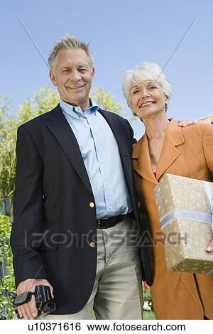 Stock Photograph - Low angle view of senior couple on birthday party with present. Fotosearch