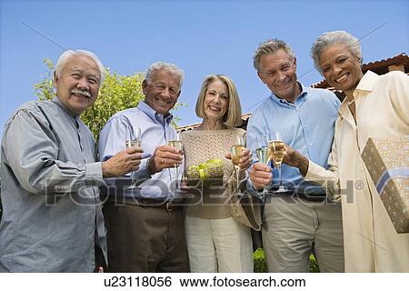 Low angle view of senior people raising toast in garden while birthday party View Large Photo Image Stock Photograph - Low angle view of senior people raising toast in garden while birthday party. Fotosearch