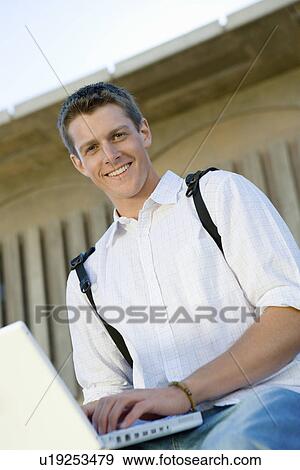 Male student using laptop outdoors, (portrait) View Large Photo Image Stock Photo - Male student using laptop outdoors, (portrait). Fotosearch