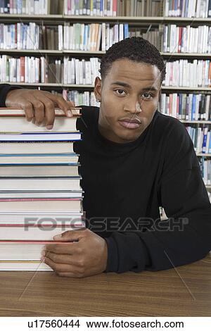Male student with a stack of books in library View Large Photo Image Picture - Male student with a stack of books in library. Fotosearch