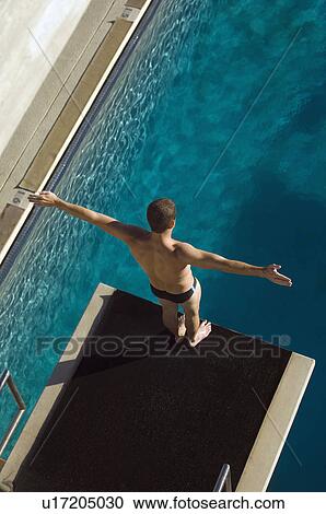 Stock Image - Male swimmer standing on diving board. Fotosearch