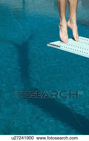 Stock Image - Male swimmer standing on diving board. Fotosearch