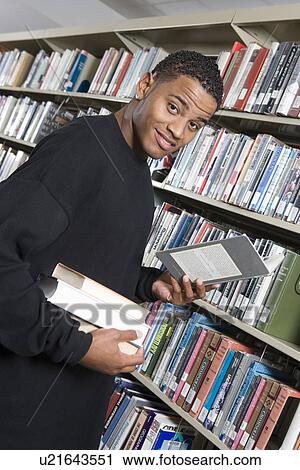Stock Image - Male University student in library, portrait. Fotosearch