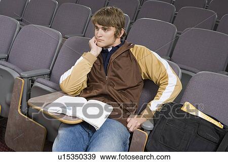 Stock Photo - Male University student sitting in lecture hall. Fotosearch