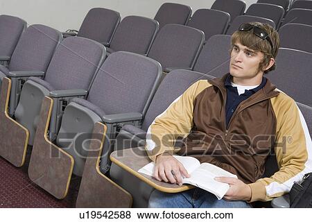 Stock Photo - Male University student sitting in lecture hall. Fotosearch