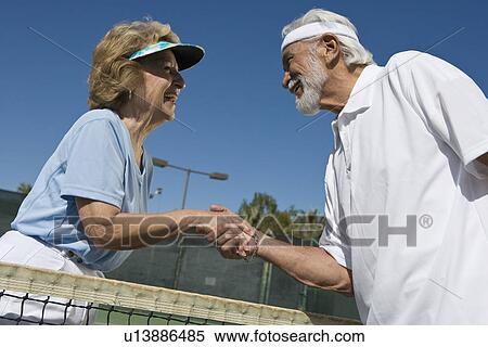 Man and woman shaking hands over tennis net View Large Photo Image Stock Photography - Man and woman shaking hands over tennis net. Fotosearch
