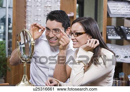 Man and woman trying on eyeglasses in store View Large Photo Image Stock Image - Man and woman trying on eyeglasses in store. Fotosearch