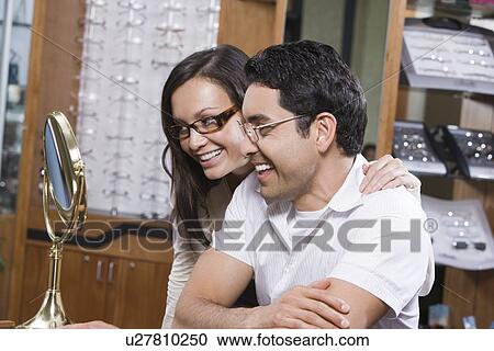 Man and woman trying on eyeglasses in store View Large Photo Image Stock Image - Man and woman trying on eyeglasses in store. Fotosearch
