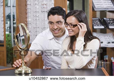 Stock Photo - Man and woman trying on eyeglasses in store. Fotosearch