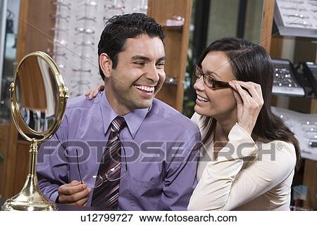 Stock Photo - Man and woman trying on eyeglasses in store. Fotosearch
