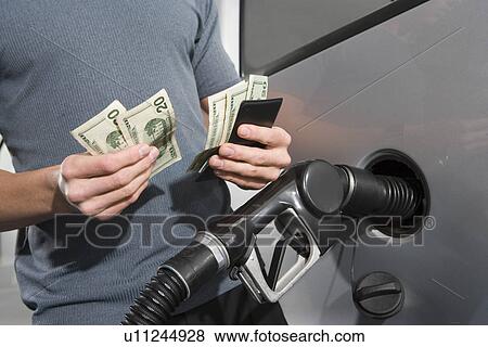 Stock Photo - Man at service station, counting money. Fotosearch