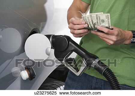 Stock Photography - Man at service station, counting money. Fotosearch