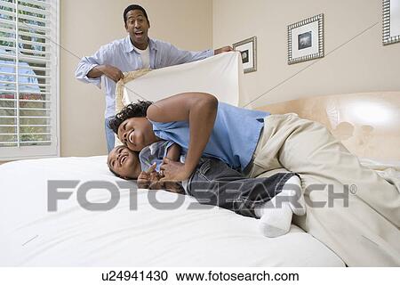 Stock Image - Man covering woman and boy with bed sheet. Fotosearch