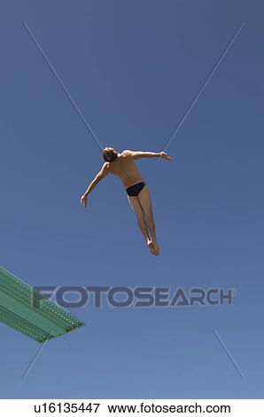 Stock Photo - Man diving from diving board, mid air. Fotosearch