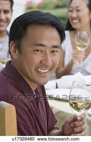 Stock Image - Man drinking wine with friends outdoors. Fotosearch