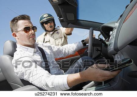 Stock Image - Man looking for driver licence while sitting in car. Fotosearch