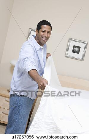 Stock Photograph - Man making a bed. Fotosearch