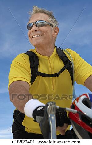Stock Image - Man on bicycle ride, portrait, low angle view. Fotosearch