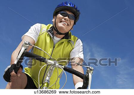 Stock Photo - Man on bicycle ride, portrait, low angle view. Fotosearch