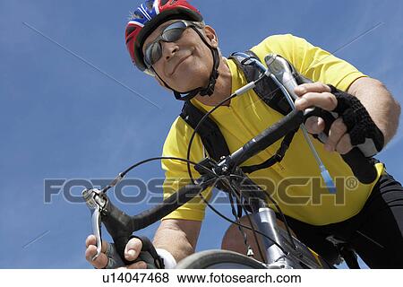 Stock Photo - Man on bicycle ride, portrait, low angle view. Fotosearch