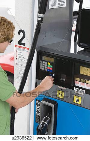 Stock Image - Man operating fuel pump payment kiosk. Fotosearch