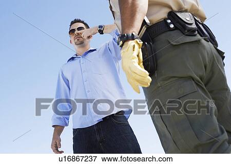 Man performing test for drink driving in front of police officer, low angle view View Large Photo Image Stock Photo - Man performing test for drink driving in front of police officer, low angle view. Fotosearch