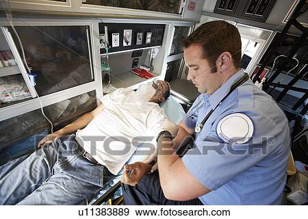 Man receiving medical aid inside ambulance View Large Photo Image Stock Photo - Man receiving medical aid inside ambulance. Fotosearch