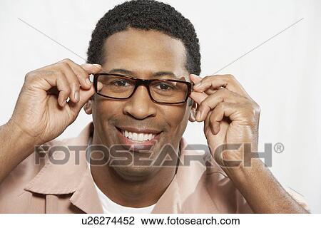Stock Image - Man trying on glasses, portrait, head and shoulders. Fotosearch